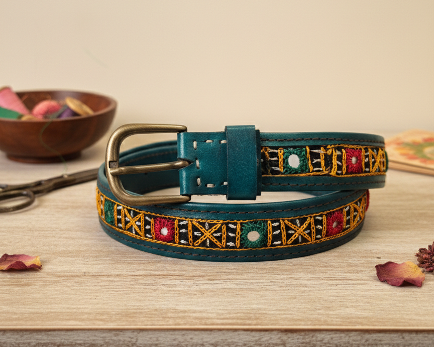 Decorative teal belt with colorful gemstones on a wooden surface