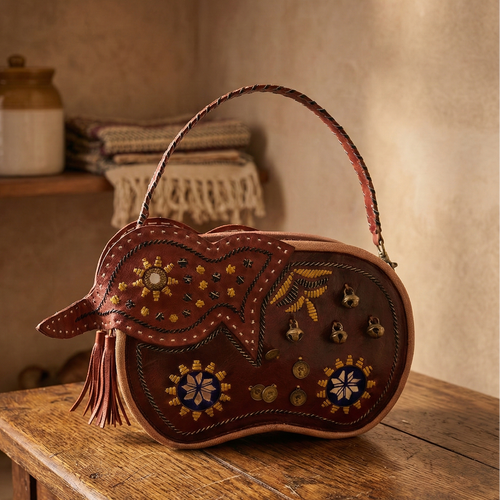 Decorative leather bag with intricate designs on a wooden table